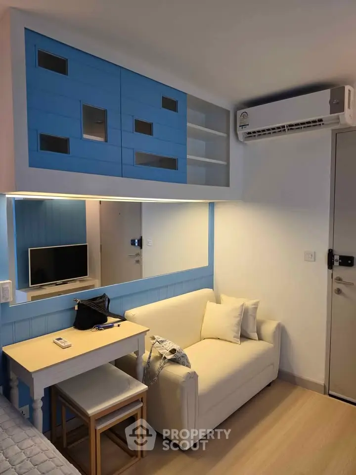 Cozy living room with modern blue cabinetry and compact sofa, perfect for urban living.