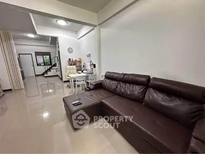 Spacious living room with modern brown leather sofa and dining area in open layout.