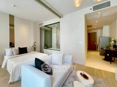Modern studio apartment with stylish decor, featuring a cozy bed, elegant sofa, and open layout.