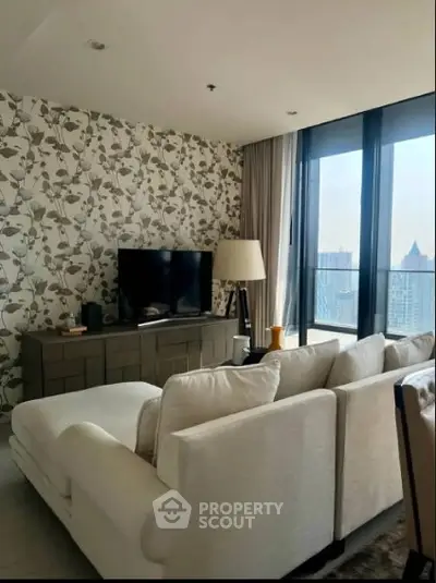 Modern living room with stylish wallpaper and city view, featuring a cozy sofa and large windows.