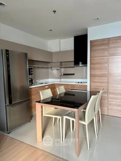 Modern kitchen with sleek appliances and dining area in contemporary apartment.