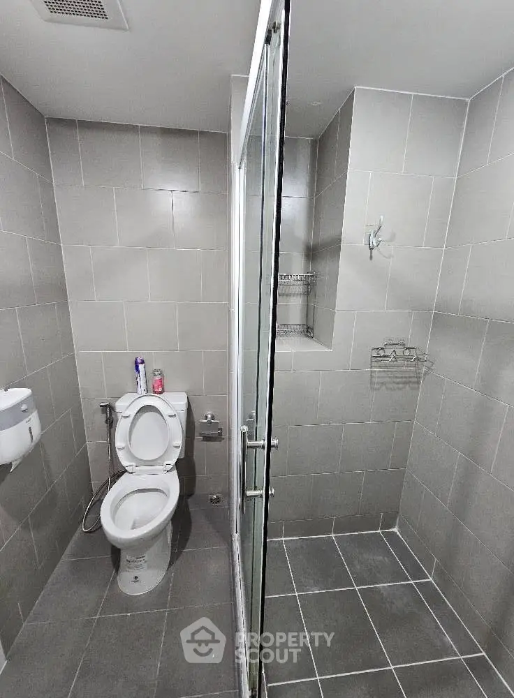 Modern bathroom with sleek gray tiles and glass shower enclosure