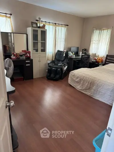 Spacious bedroom with wooden flooring, cozy bed, and modern furniture, perfect for relaxation and comfort.