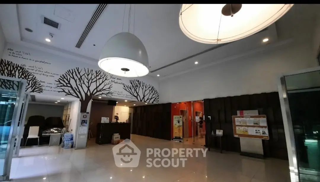 Spacious modern lobby with unique tree wall art and elegant lighting fixtures.
