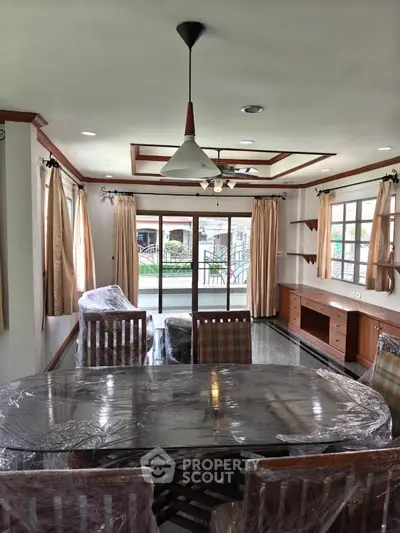 Spacious living room with elegant dining area and large windows offering natural light.