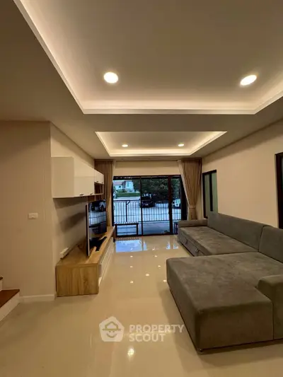 Spacious modern living room with sleek design and large windows opening to a balcony.