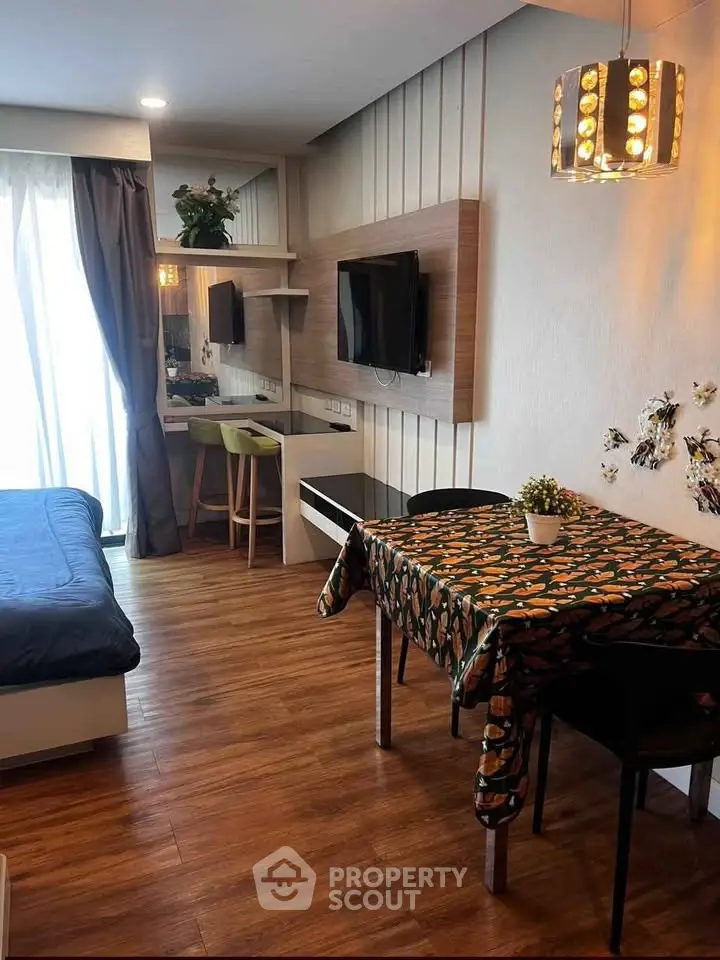 Modern studio apartment with stylish decor, featuring a cozy bed, dining area, and wall-mounted TV.