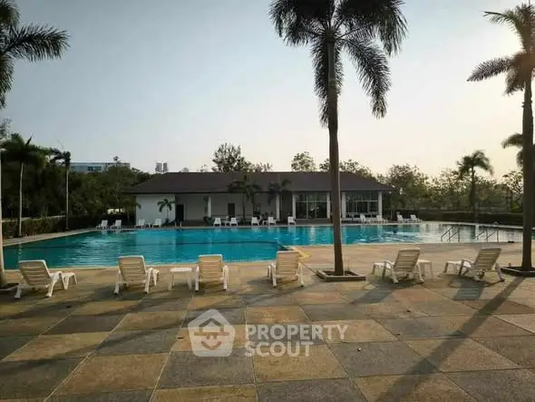 Luxurious outdoor pool area with palm trees and sun loungers, perfect for relaxation.