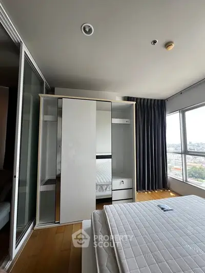 Modern bedroom with large windows and sleek wardrobe in a high-rise apartment.