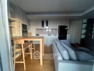 Modern open-plan living room with kitchen featuring sleek cabinetry and cozy seating area.