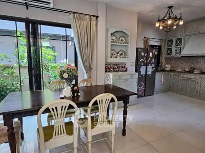 Charming kitchen with elegant dining area and garden view, featuring classic cabinetry and modern appliances.