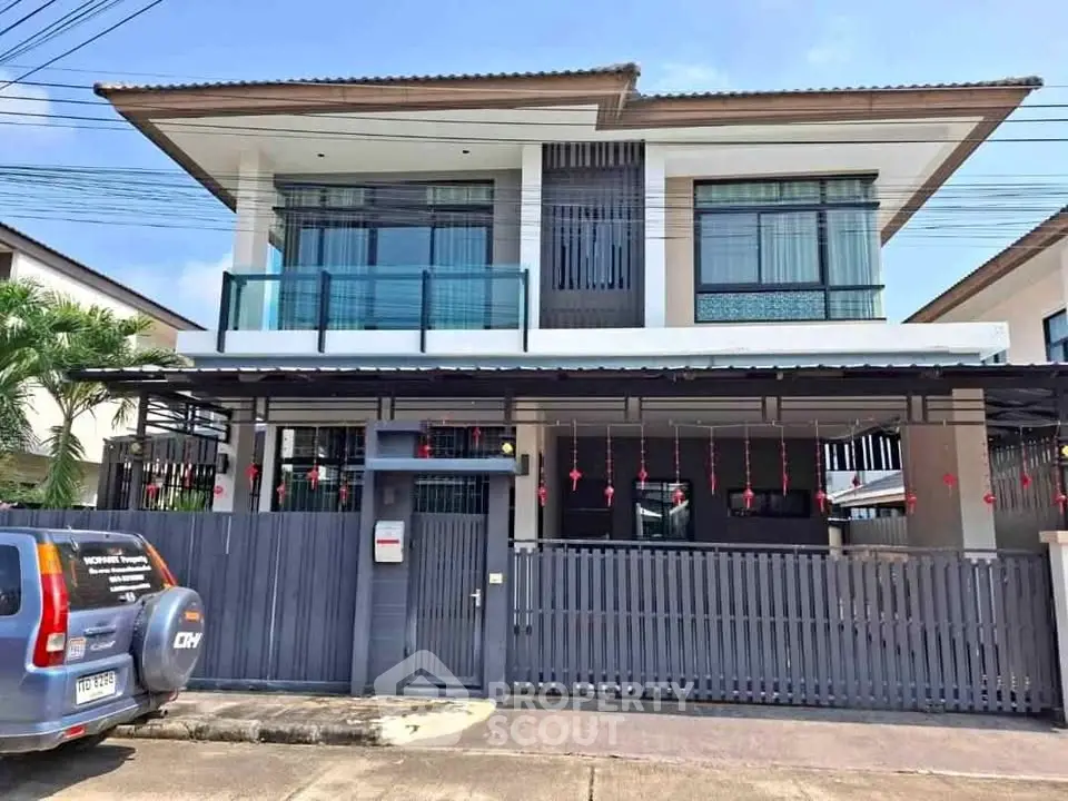 Modern two-story house with sleek design and spacious balcony in a suburban neighborhood.