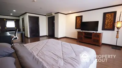 Spacious bedroom with modern decor and large TV in luxury apartment