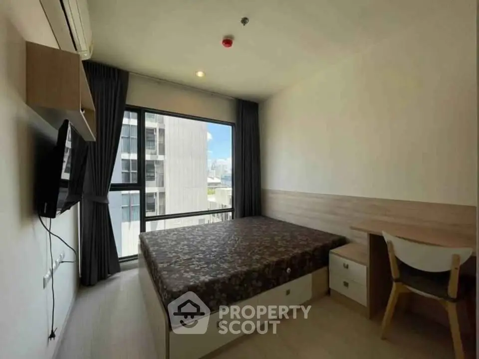 Modern bedroom with large window and city view, featuring a cozy bed and stylish furniture.