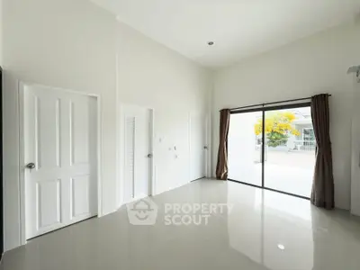 Spacious empty room with large sliding glass doors and high ceiling, perfect for customization.