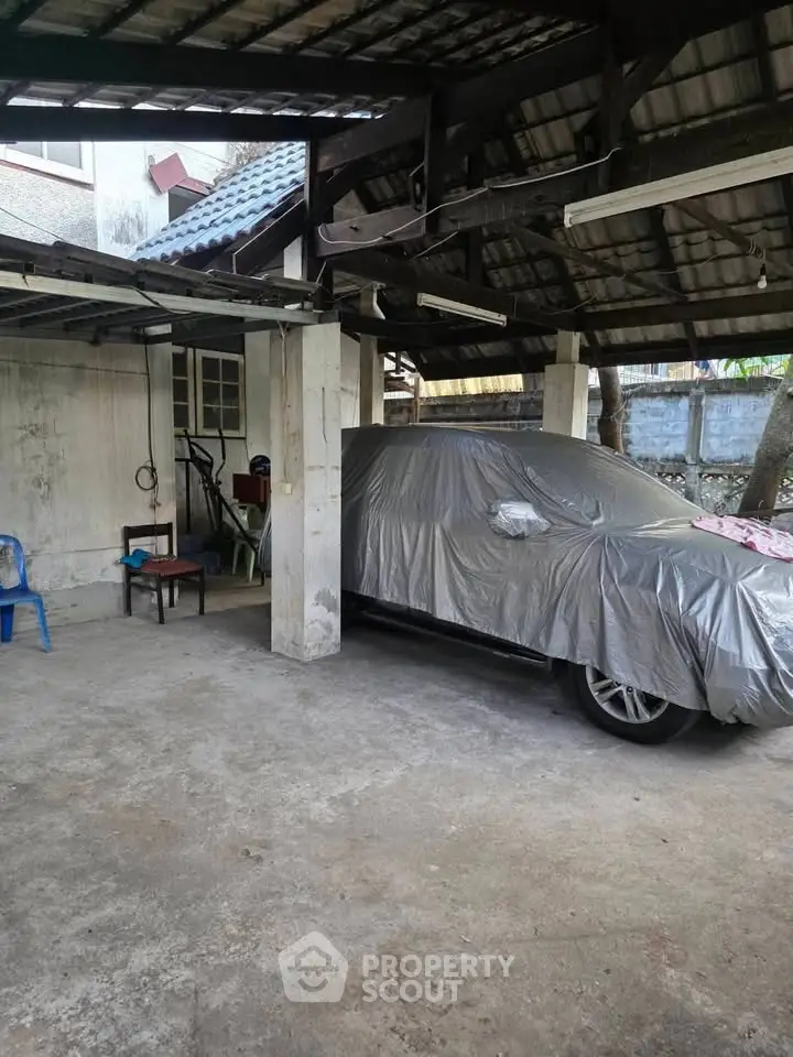 Covered car in spacious residential parking area with sturdy roof structure.