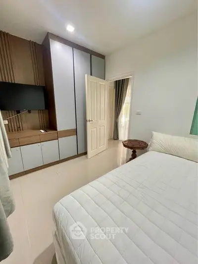 Modern bedroom with sleek wardrobe and wall-mounted TV, perfect for cozy living.