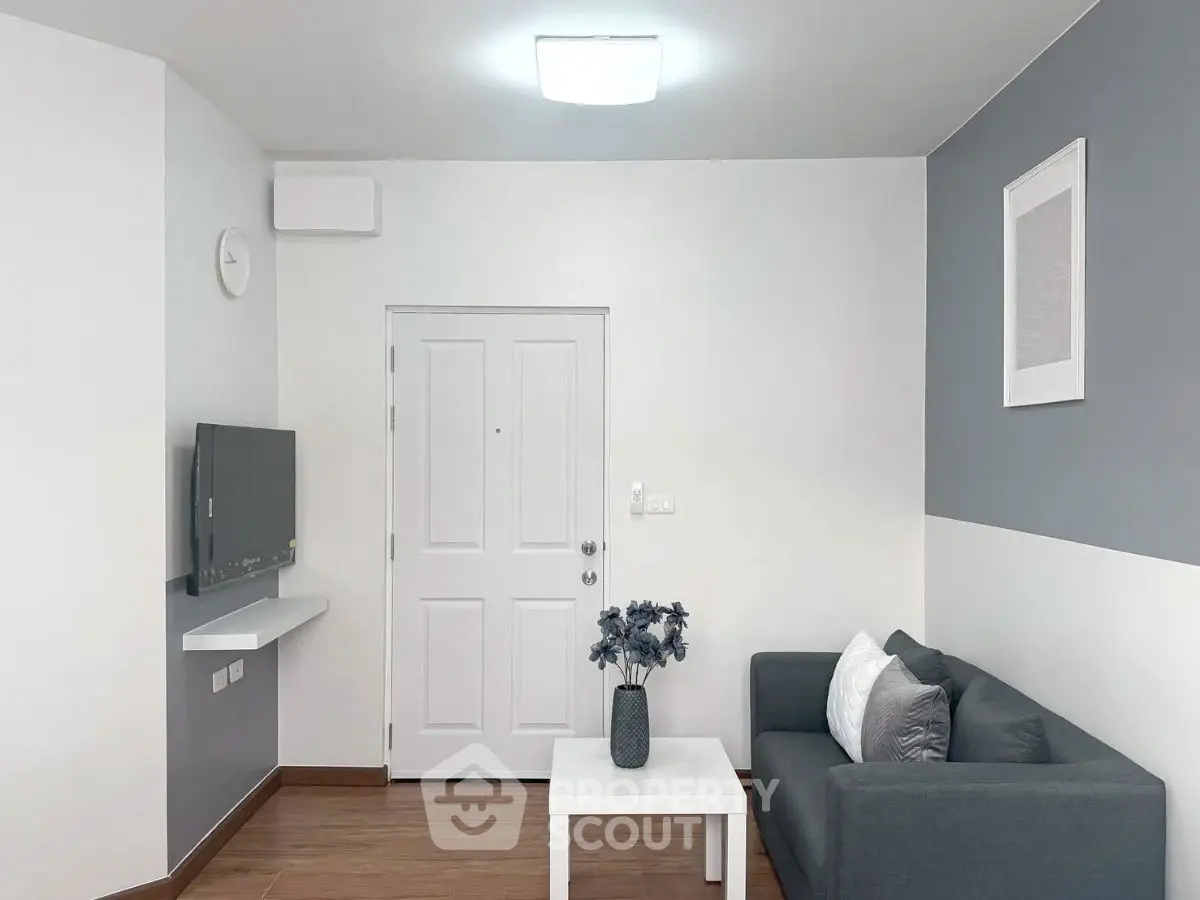 Modern minimalist living room with sleek gray sofa and wall-mounted TV