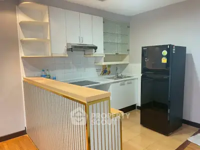 Modern kitchen with sleek black fridge and open shelving in stylish apartment.