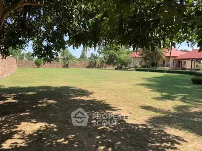 Spacious garden area with lush greenery and a charming house in the background, perfect for outdoor activities.