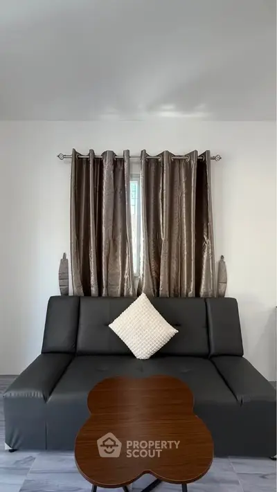 Modern living room with sleek black sofa and elegant curtains, perfect for stylish urban living.