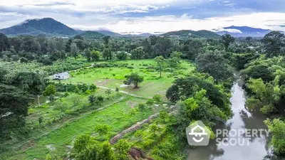 Scenic aerial view of lush green landscape with river and distant mountains, perfect for nature lovers.