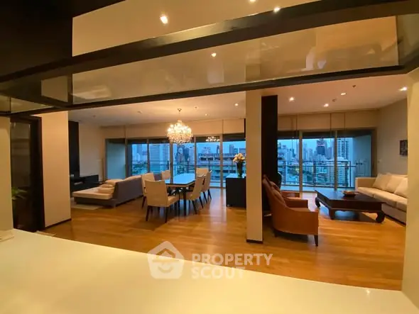 Luxurious open-plan living and dining area with city view, featuring elegant furniture and ambient lighting.
