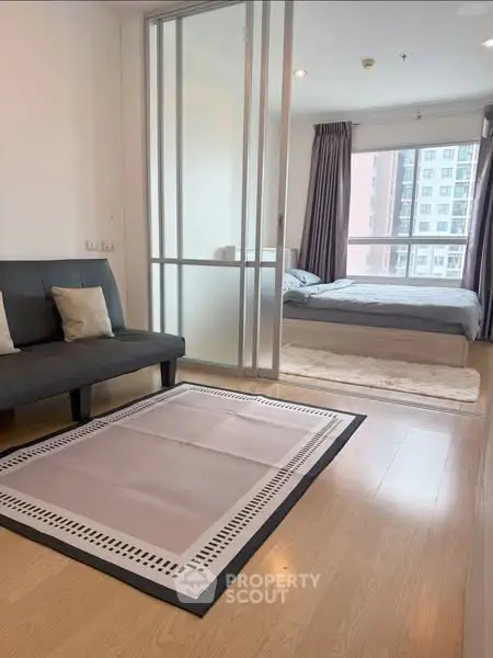 Modern apartment with open living area and bedroom, featuring large windows and sleek design.