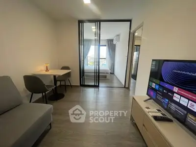 Modern living room with sleek design and smart TV, adjacent to a cozy bedroom with city view.