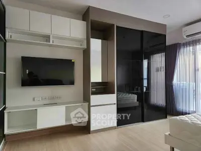 Modern bedroom with sleek design, featuring a wall-mounted TV and large glass wardrobe.