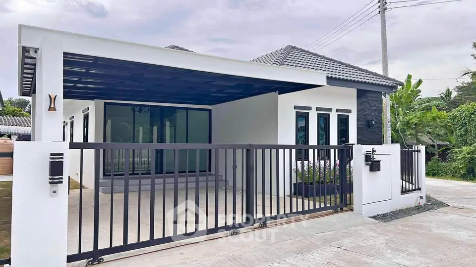 Modern single-story house with gated driveway and sleek exterior design.