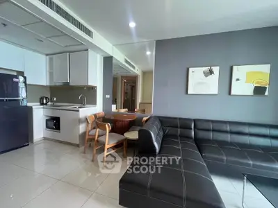 Modern living room with sleek black sofa and compact kitchen area