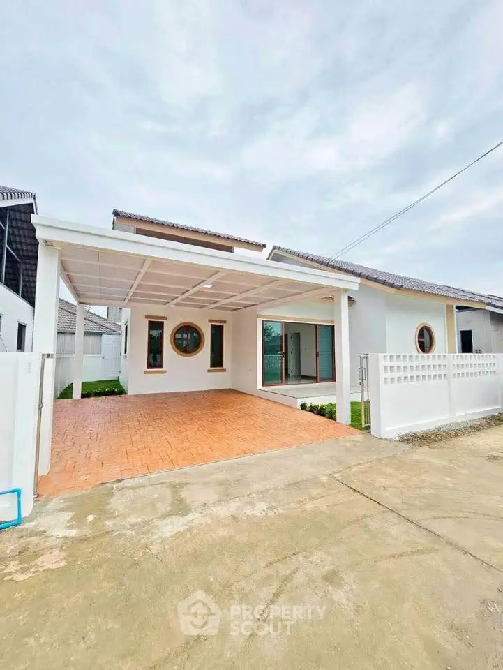 Charming single-story white house with a spacious carport and modern circular windows.