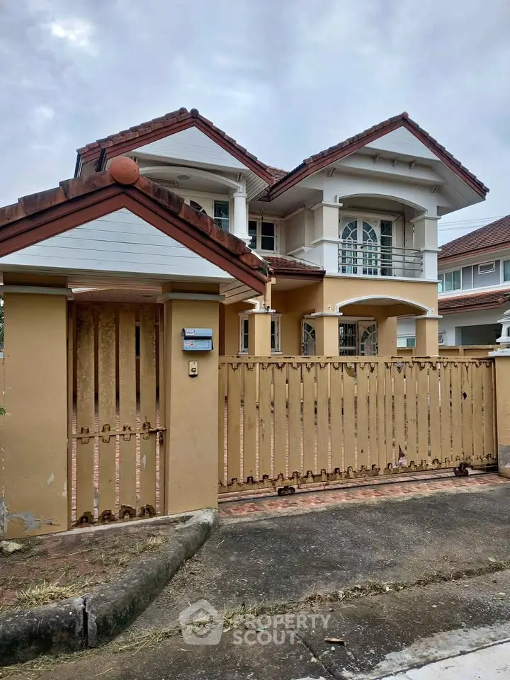 Charming two-story house with gated entrance and classic architectural design.