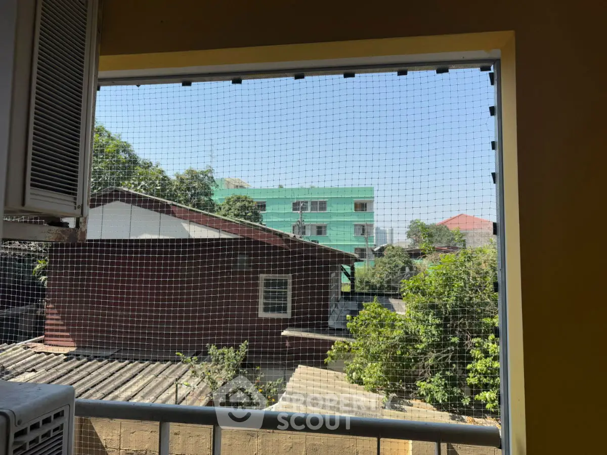 Charming balcony view with lush greenery and neighboring buildings.
