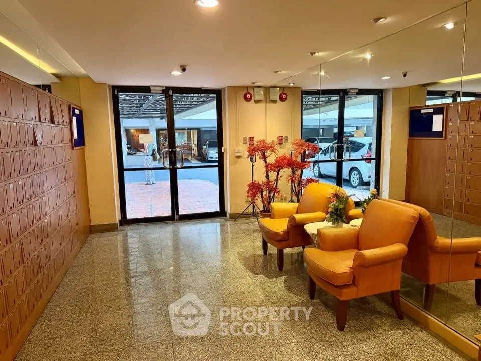 Elegant building entrance with cozy seating and mirrored walls, offering a welcoming ambiance.