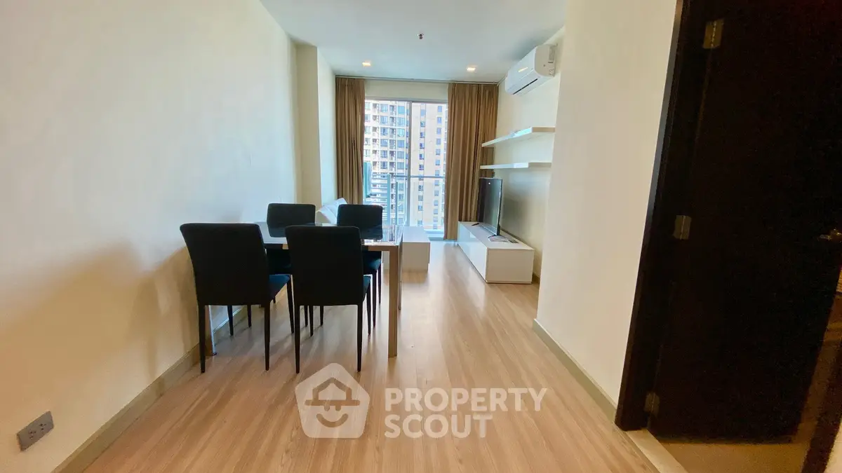 Modern living room with dining area and city view, featuring sleek furniture and natural light.