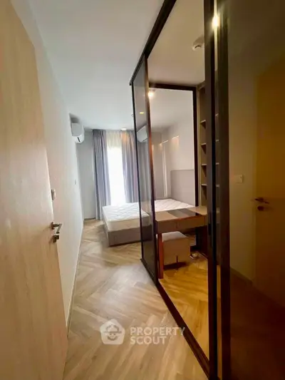 Modern bedroom with stylish herringbone flooring and mirrored closet doors, offering a sleek and contemporary design.