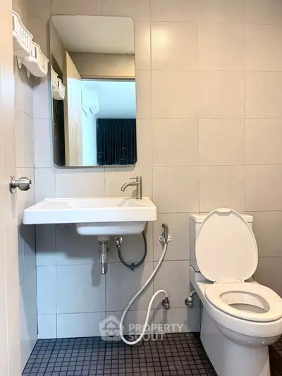 Modern bathroom with sleek fixtures and tiled walls, featuring a wall-mounted sink and toilet.
