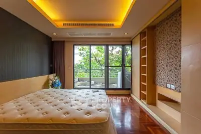 Spacious bedroom with large windows and balcony access, featuring elegant wood flooring and built-in storage.