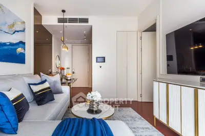 Modern living room with elegant decor and large TV, featuring stylish furniture and contemporary art.