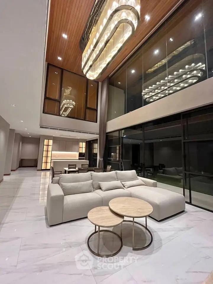 Luxurious modern living room with high ceilings, elegant chandelier, and spacious open layout.
