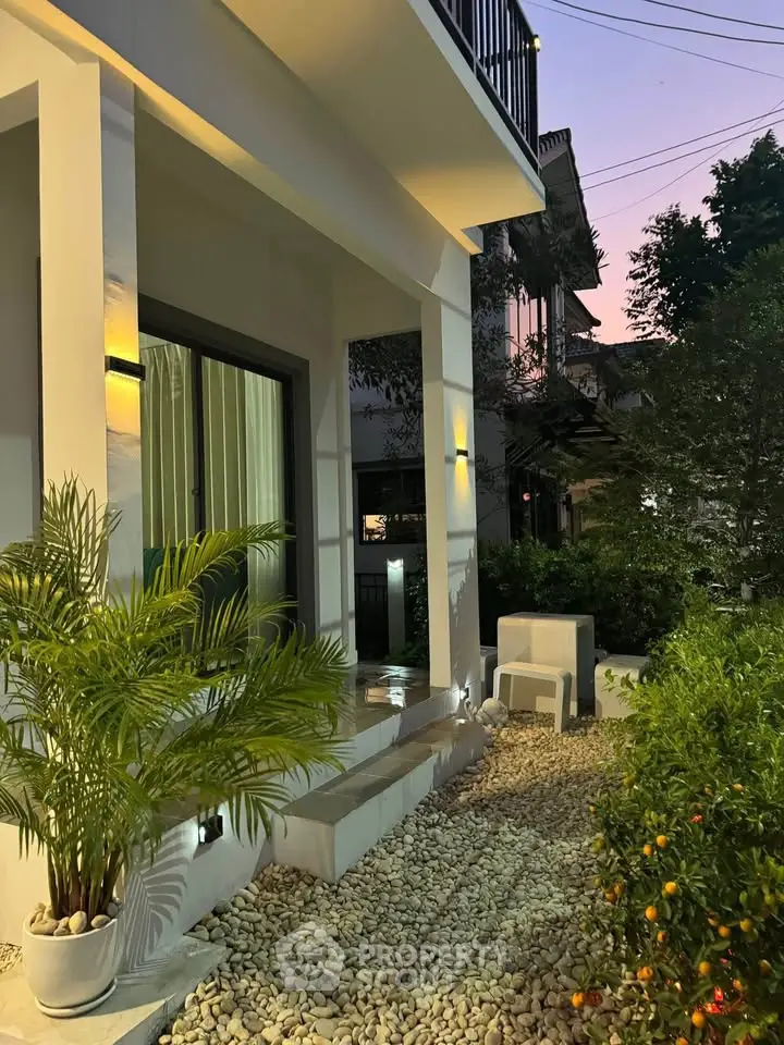Charming modern home exterior with lush garden and ambient lighting at dusk.