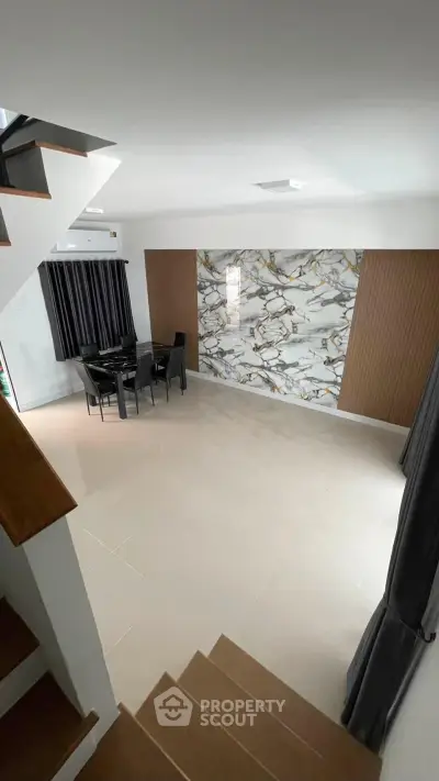 Spacious modern living room with elegant marble accent wall and dining area, perfect for entertaining.