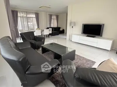 Spacious living room with modern black leather sofas and large windows