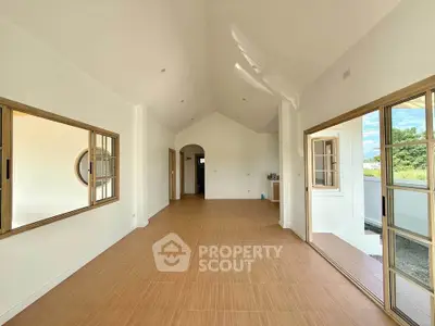 Spacious open-plan living area with large windows and high ceilings, offering abundant natural light and outdoor views.