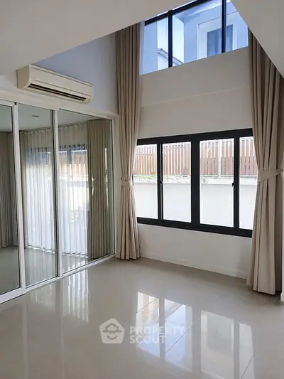 Spacious modern living room with high ceilings and large windows, perfect for natural light.
