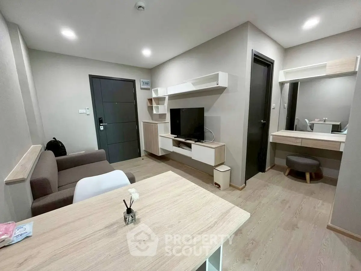 Modern living room with sleek furniture and neutral tones, featuring a TV unit and cozy seating area.