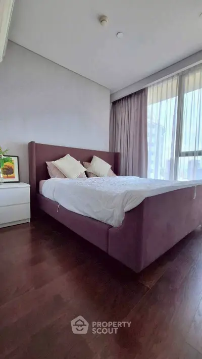 Spacious bedroom with elegant bed and large windows offering natural light.