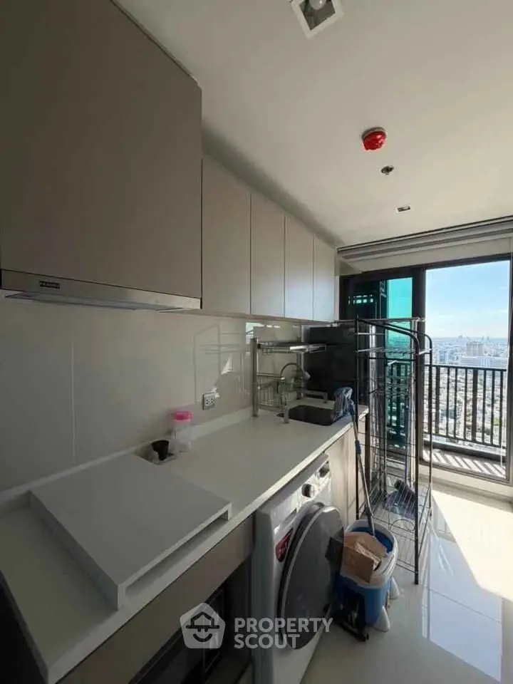 Modern kitchen with sleek appliances and balcony view in high-rise apartment.